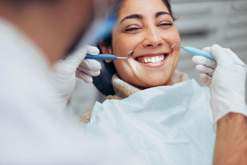 Smiling woman receiving a dental check-up, showcasing comfort and trust in professional dental care. Experience confident, compassionate dentistry today!