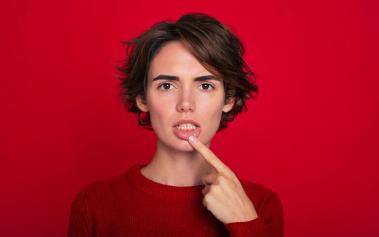 Close-up portrait of gum inflammation. A cropped shot of a young woman showing red bleeding gums isolated on a bright red background. Dentistry, dental care