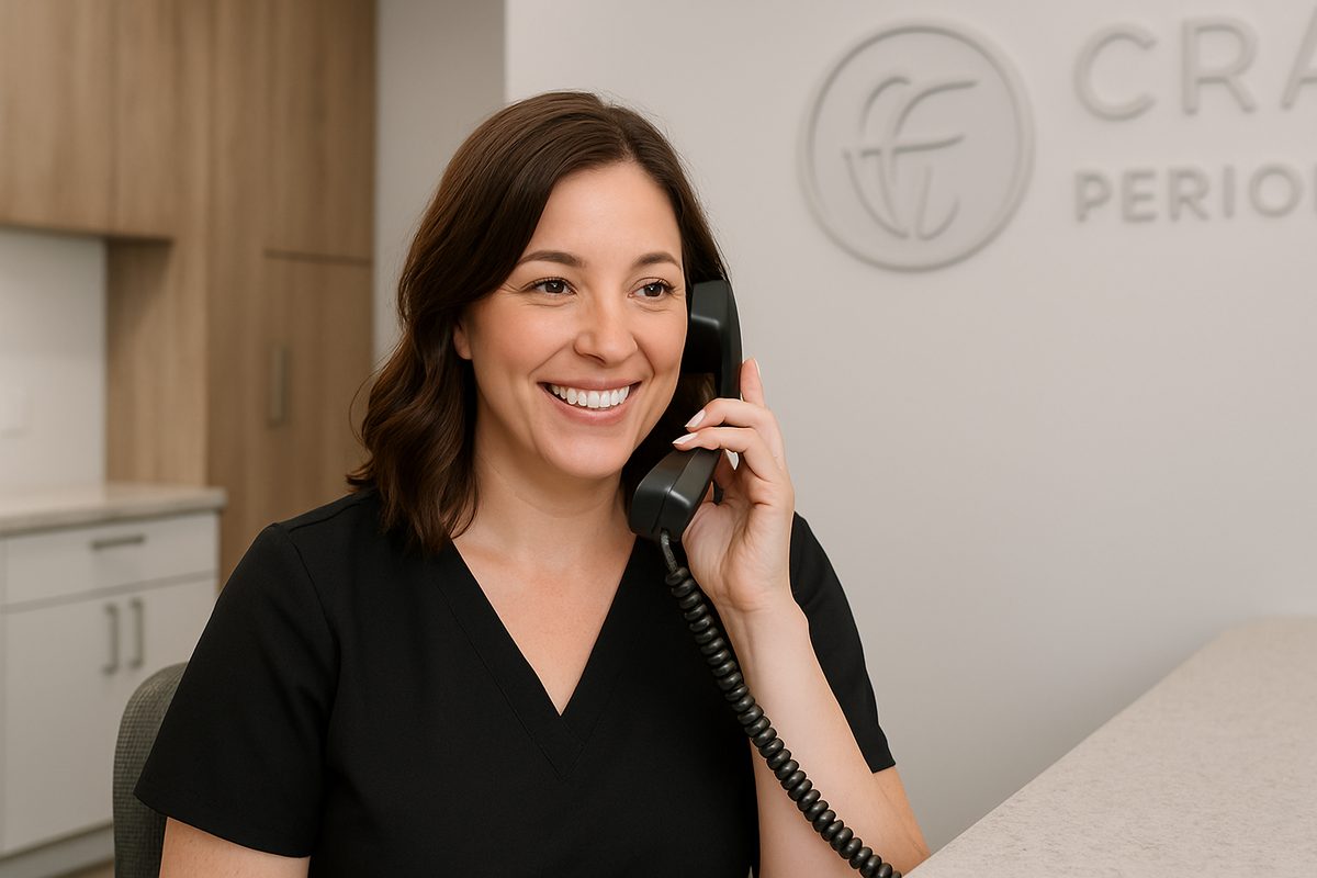 A friendly dental receptionist is on the phone, helping a patient verify their insurance coverage. The office setting is clean and modern, with a subtle logo of Eastman Craighead Periodontics in the background. No text on image.